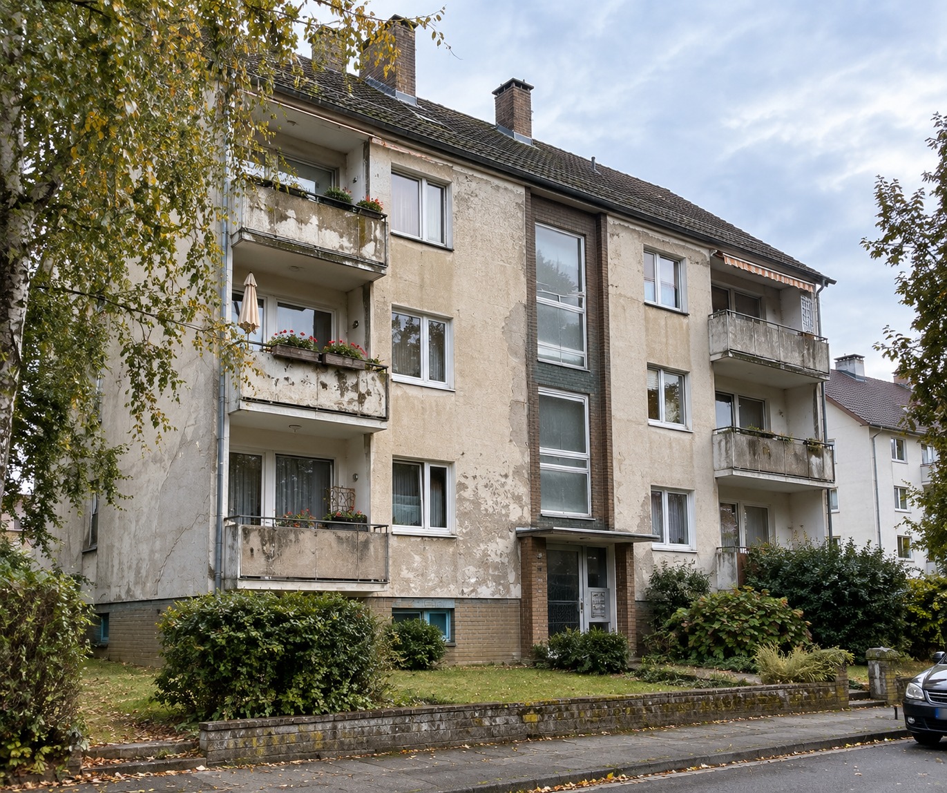 Mehrfamilienhaus mit sanierungsbedürftiger Putzfassade und Balkonen im Bestand